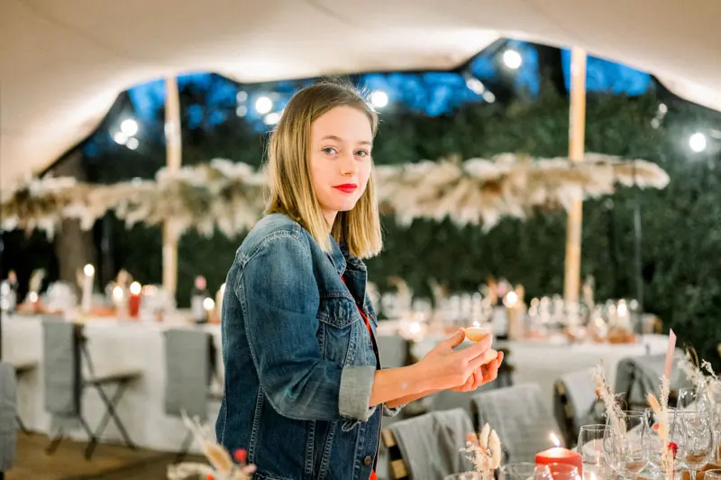 Guest in a denim jacket under the pampas-decorated tent with laid tables