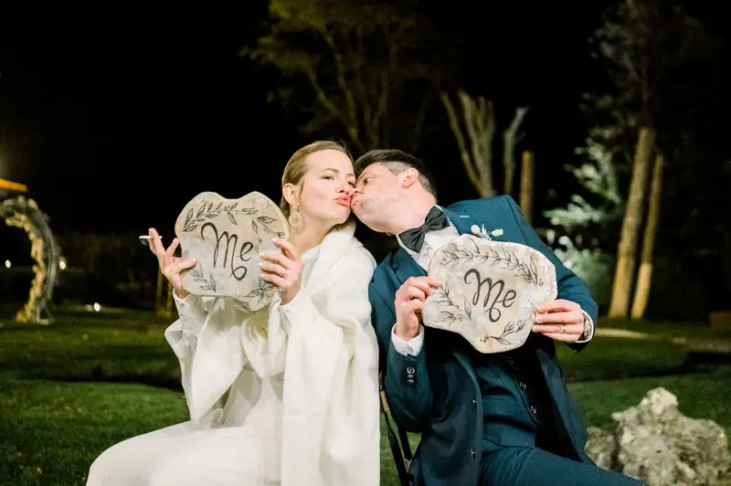 Bride and groom holding up "Me" signs during an evening game