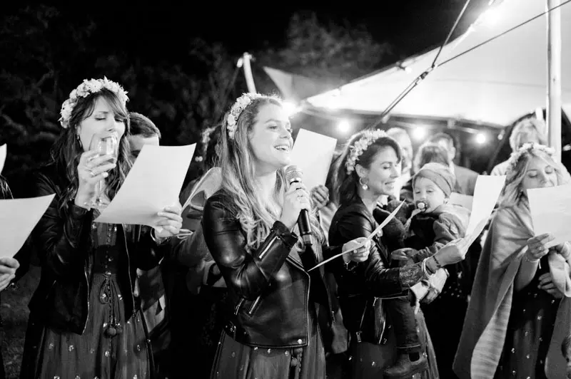 Guests singing a song for the couple, in black and white