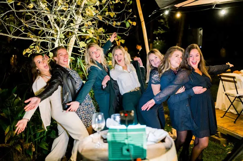 Group of friends striking playful poses around a gift during the evening