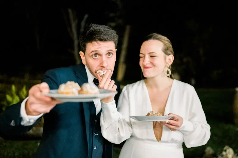 Bride and groom tasting the cream puff dessert, plates in hand