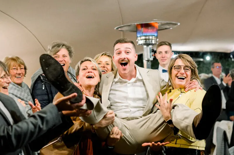 Guests cheerfully lifting a friend up under the tent
