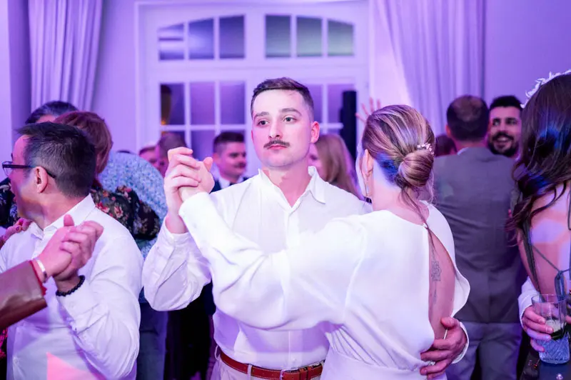 Guests dancing on the dance floor under purple party lights