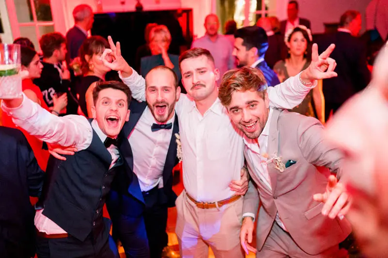 Groom's friends goofing around on the dance floor under red lights