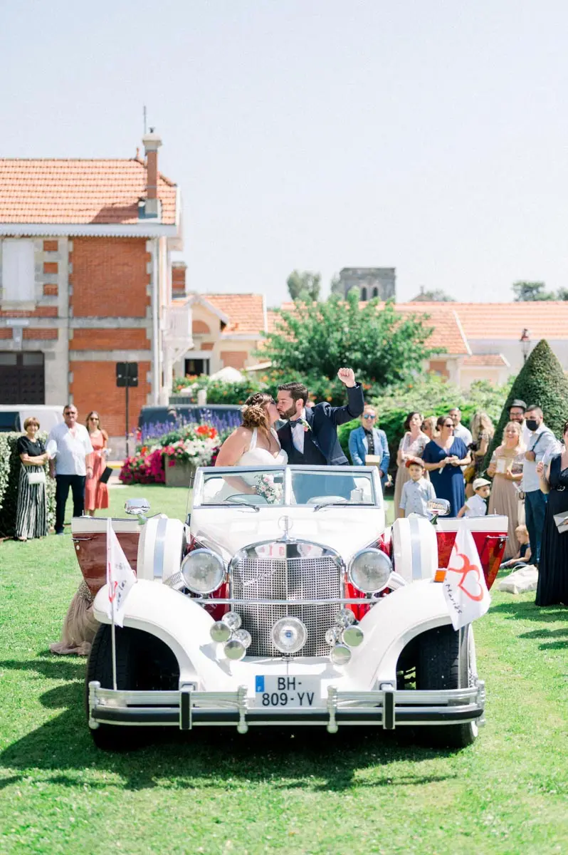 White vintage car decorated with flowers outside the town hall, guests around it