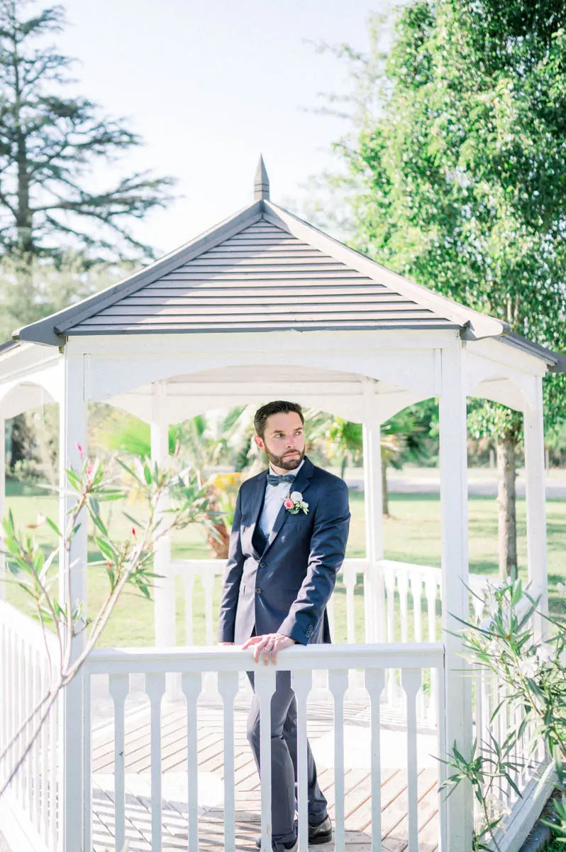 Groom posing in the white gazebo in the grounds of Domaine de Cordet