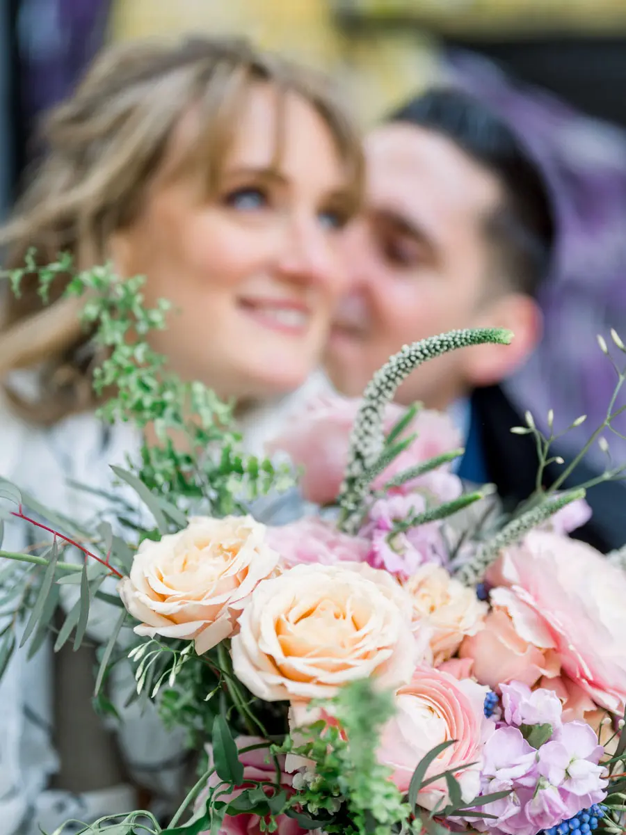 The bride's smile behind her bouquet of roses and foliage