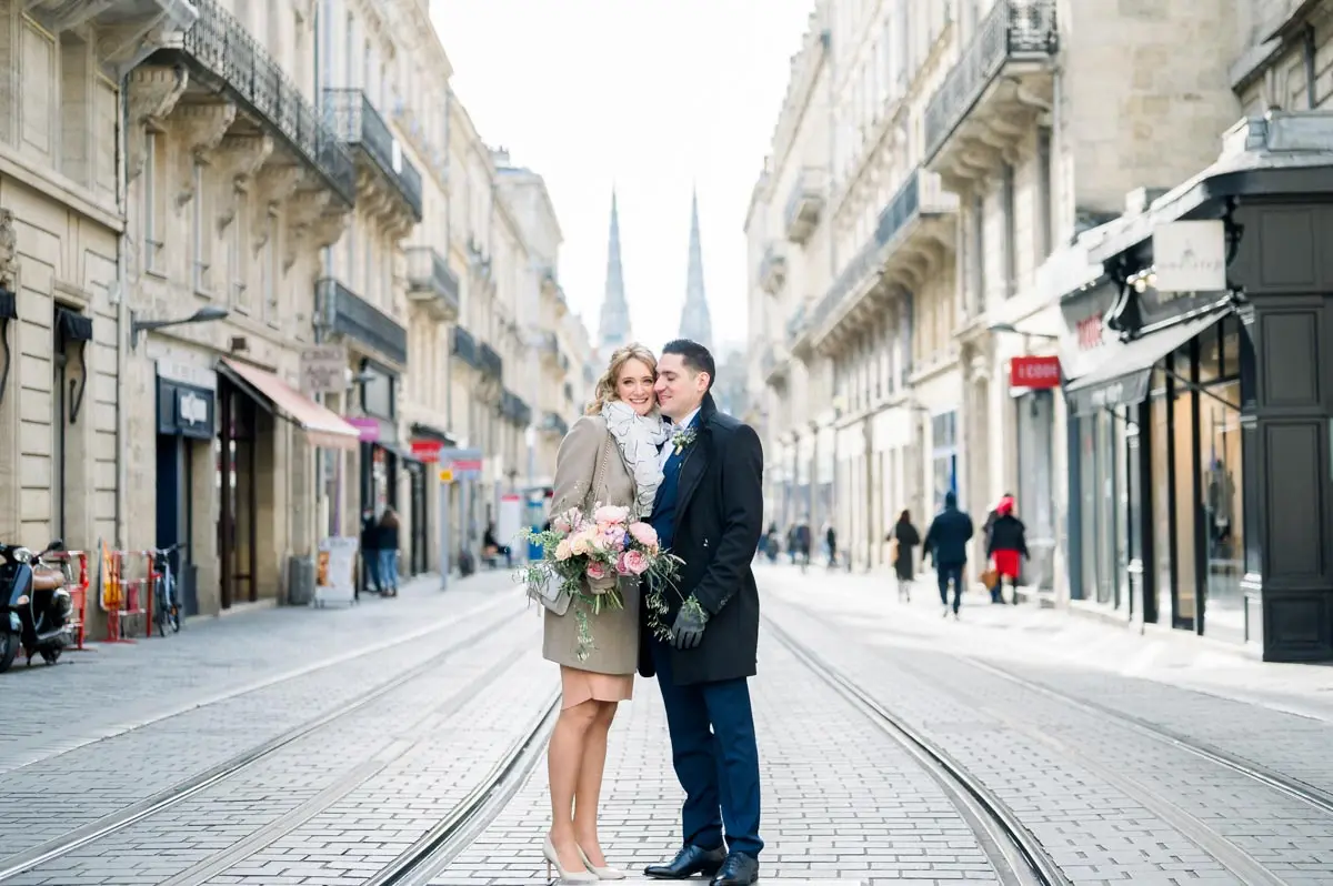 The couple in a pedestrian street in Bordeaux, cathedral spires in the distance