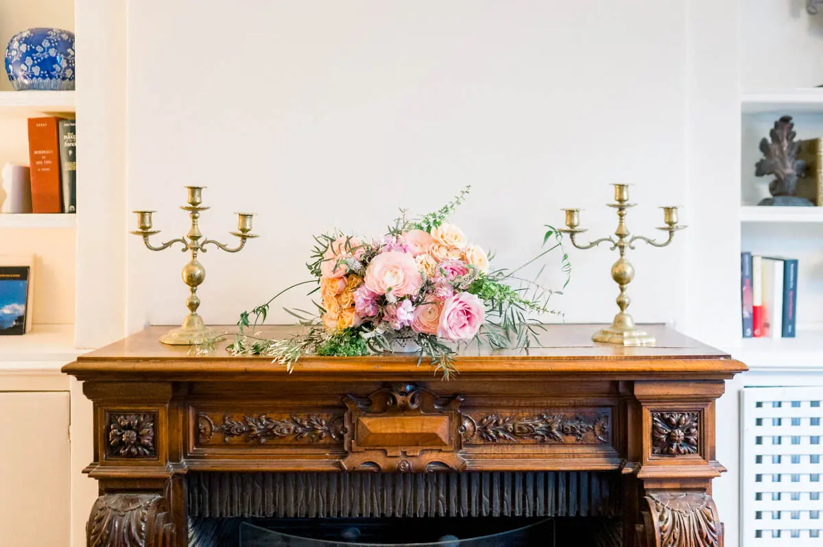 Bridal bouquet on a carved wooden mantelpiece between two candlesticks