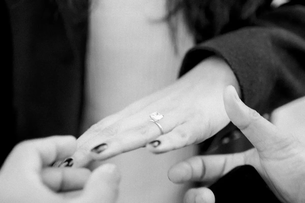 He slips the engagement ring onto Nisha's finger, black and white