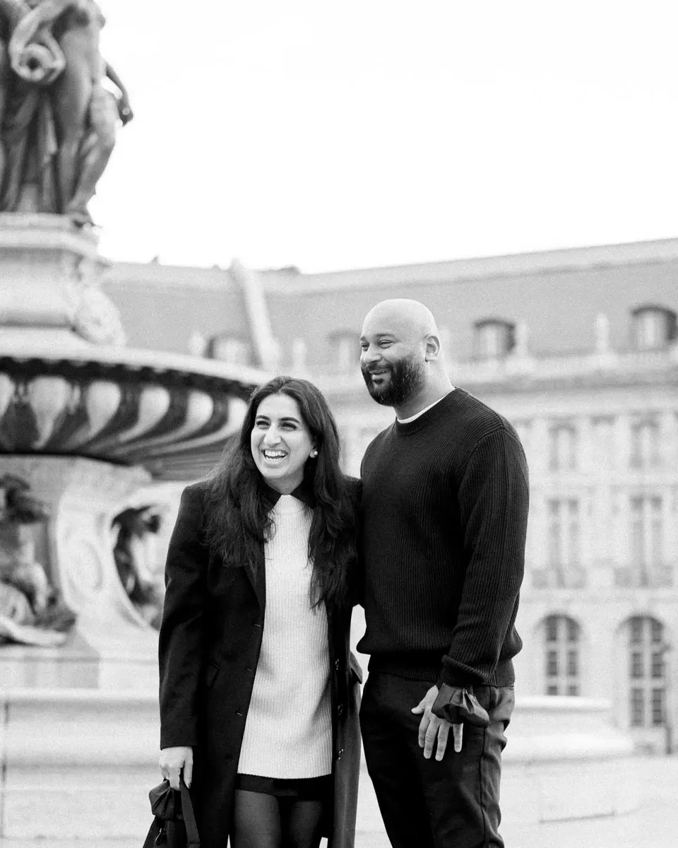 Newly engaged couple smiling by the Place de la Bourse fountain, black and white