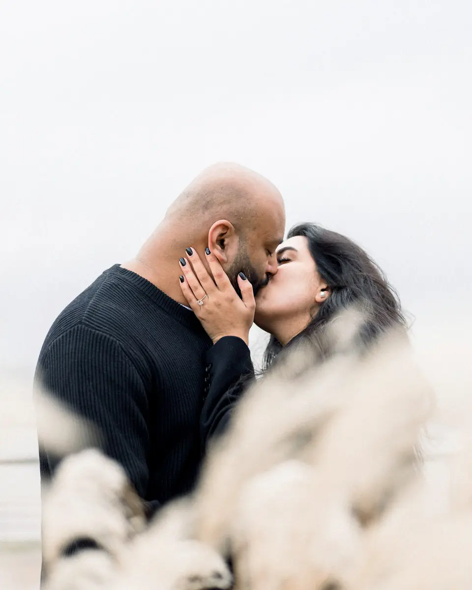 Hardik and Nisha kissing behind pampas plumes in Bordeaux