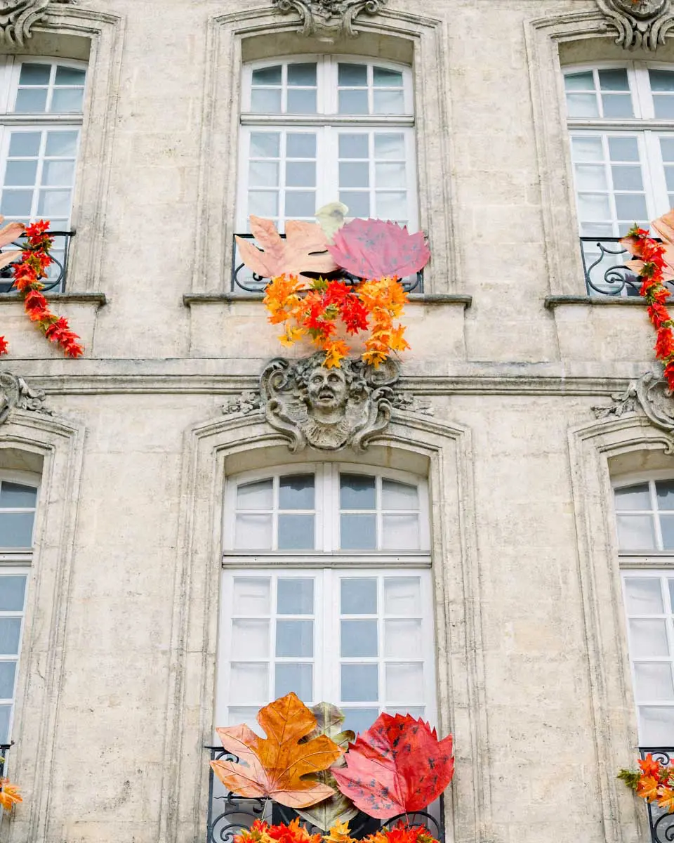 Stone facade adorned with orange and red floral decorations in Bordeaux