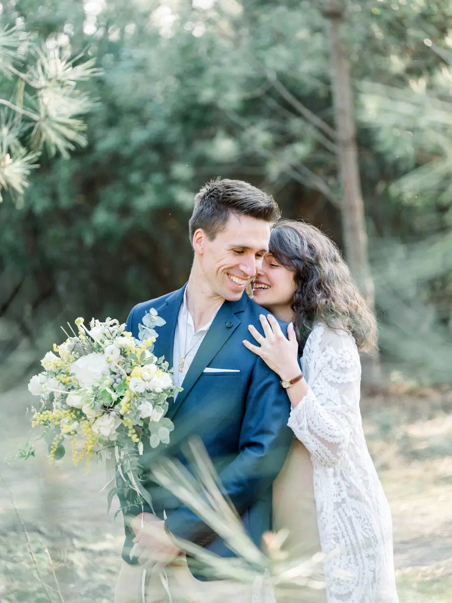 Stéphanie nestled against Yann, who holds the bouquet among tall grasses