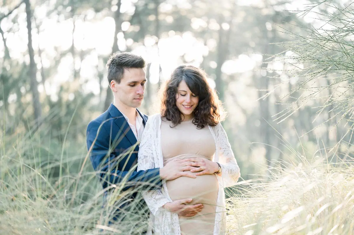 Expectant couple among tall grass on Arcachon Bay