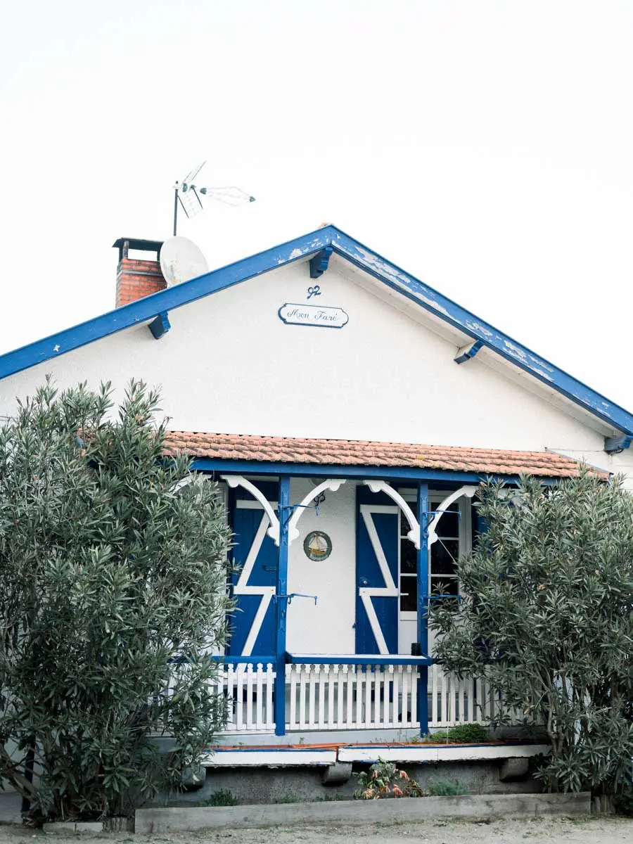White cottage with blue woodwork in the village of L'Herbe