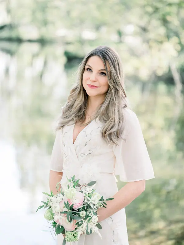 Portrait of the bride-to-be holding her bouquet in front of the pond