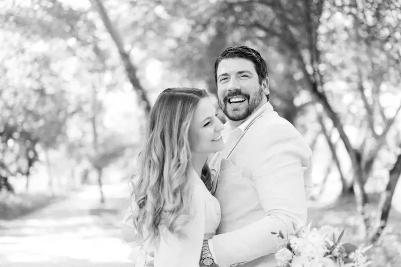 Couple smiling cheek to cheek under the trees of Parc Majolan, black and white