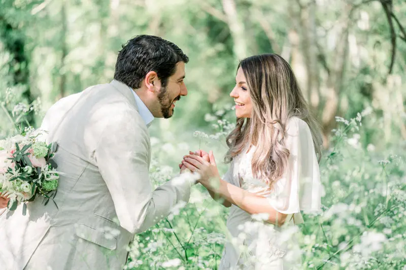 The couple holding hands and smiling at each other amid the greenery