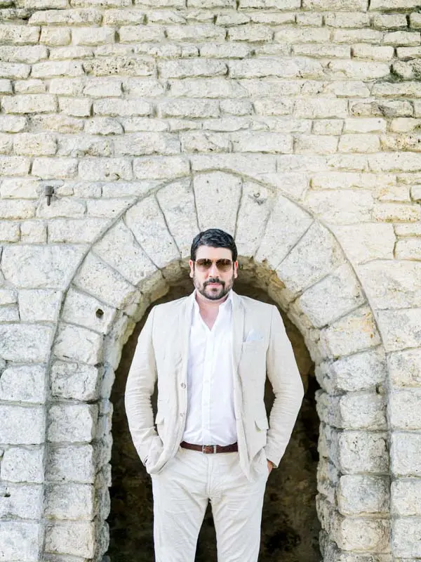 Groom-to-be in a light suit beneath a stone archway in Parc Majolan
