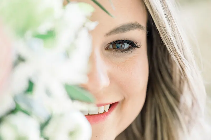 Close-up of the fiancée's smile behind white flowers