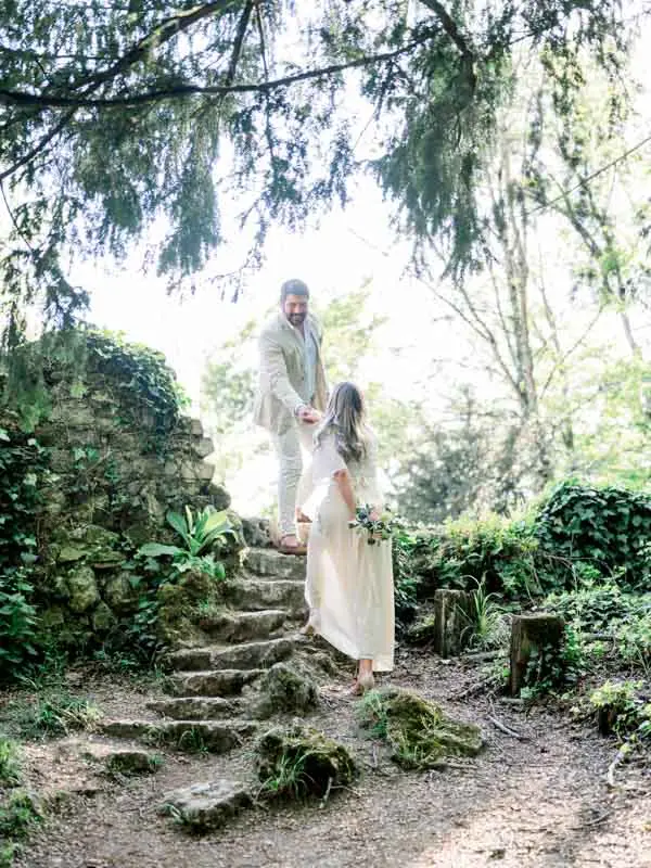 The couple walking down a mossy stone staircase in the park