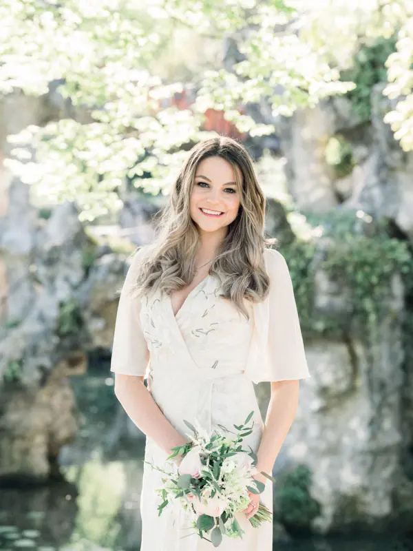 Portrait of the smiling fiancée in a cream dress in front of the rocks