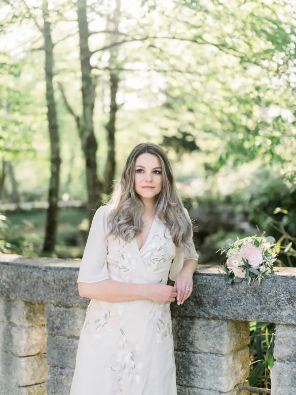 The fiancée posing against the balustrade, her bouquet resting beside her