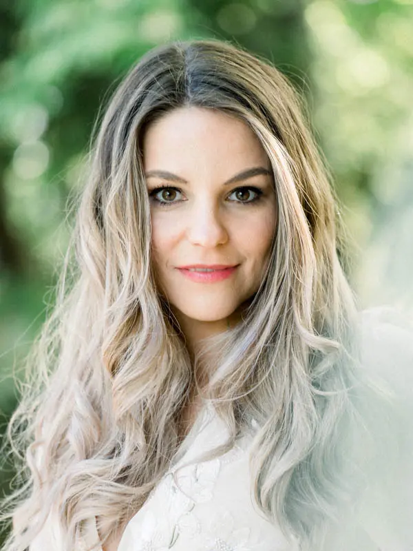 Bright portrait of the fiancée with long wavy hair amid the greenery