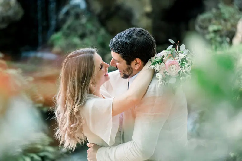 The couple embracing and smiling at each other by the Parc Majolan waterfall