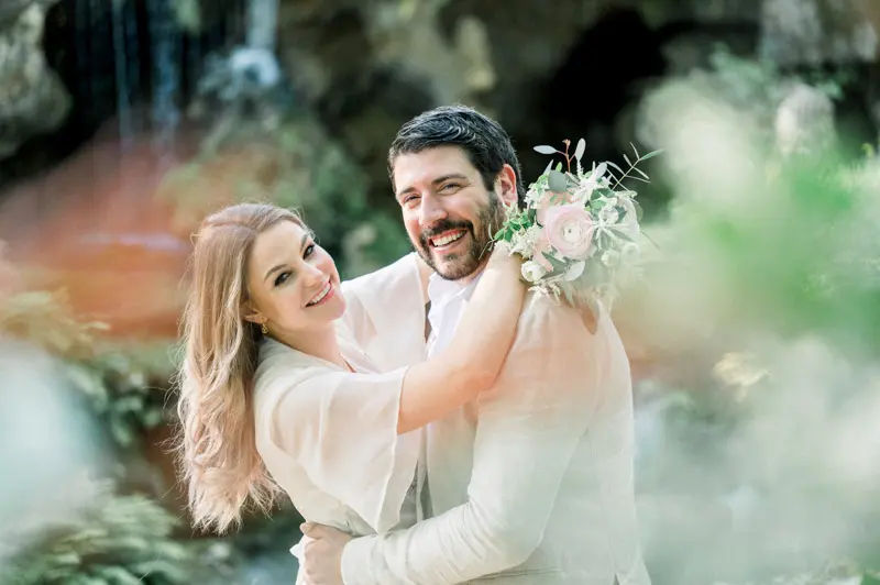 The laughing couple embracing, blurred foliage in the foreground