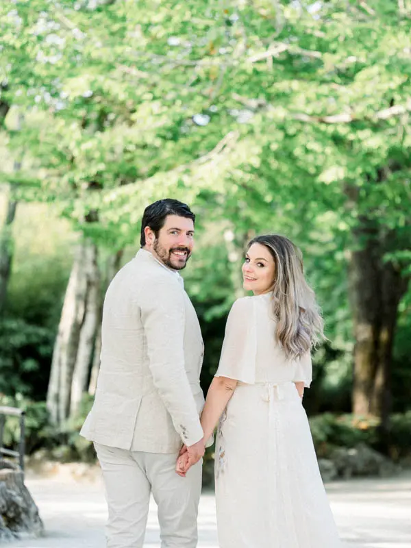 The couple holding hands and looking back at the camera with a smile
