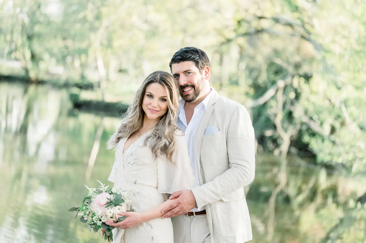 Couple embracing by the water during an engagement session at Parc de Majolan