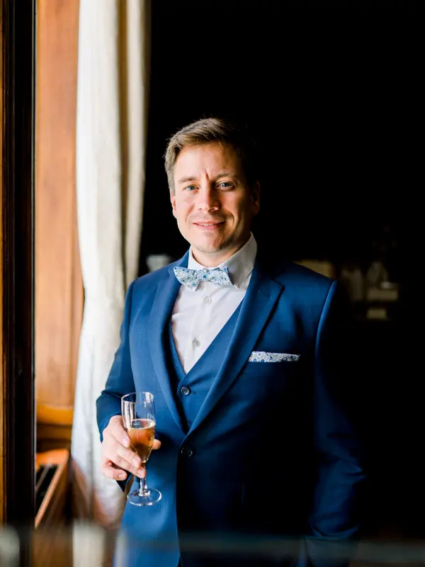 Groom in a blue suit with a glass of champagne, Château Pape Clément