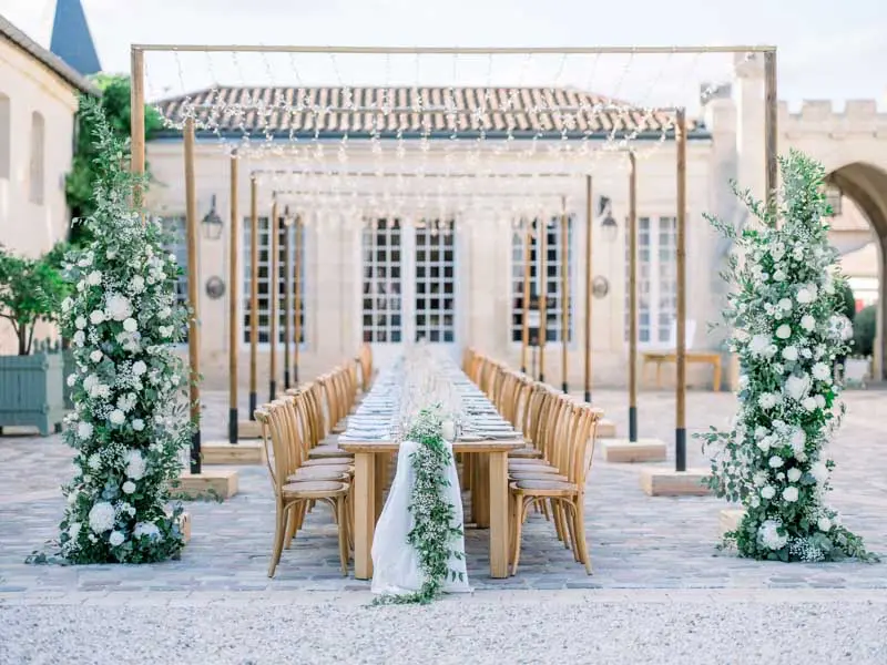 Long table and floral arches in the courtyard of Château Pape Clément