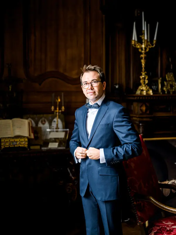 Groom in a navy tuxedo in a wood-panelled room, Château Pape Clément