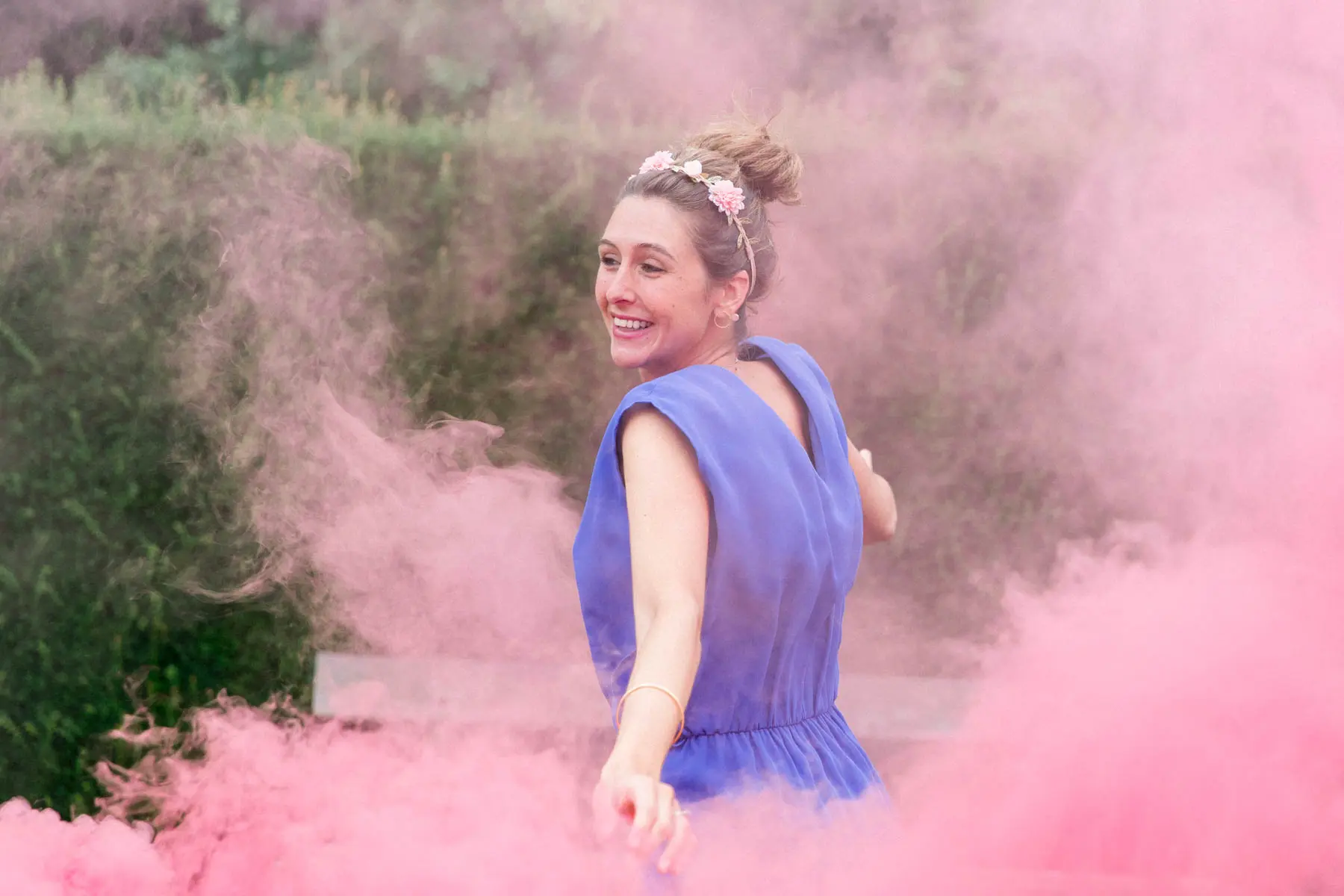 Young woman in a purple dress amid pink smoke, hen party at the Barails reserve