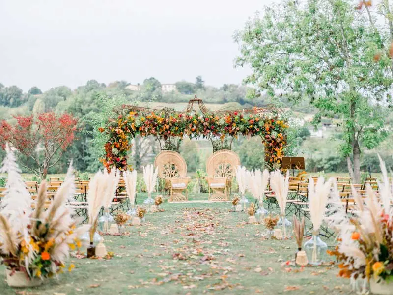 Outdoor wedding ceremony aisle with floral arch at Château de Garde