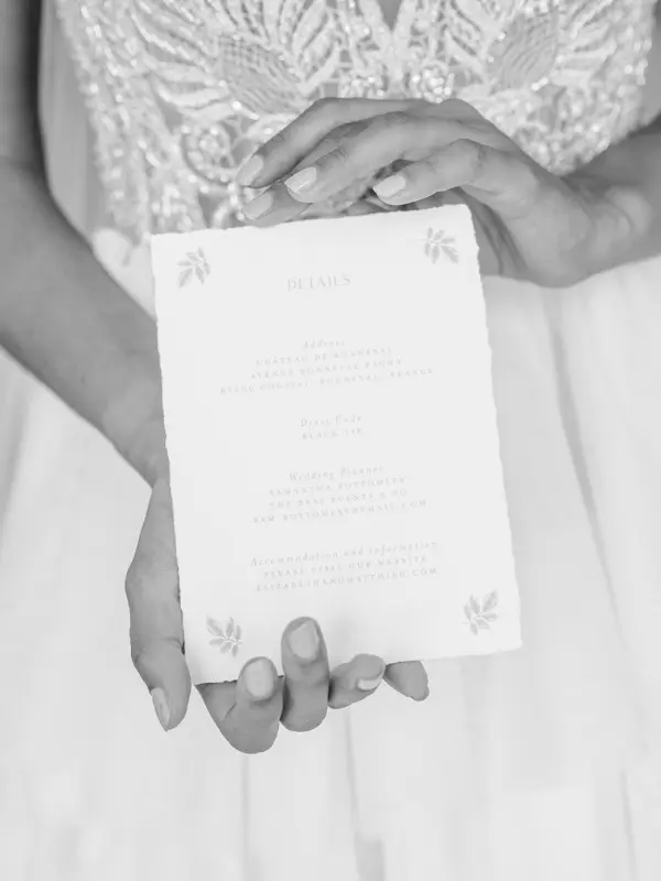 Bride holding the wedding menu at Château Gassies, in black and white