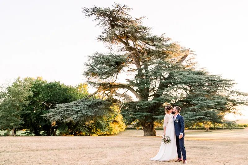 Bride and groom beneath a cedar tree at Château de Seguin