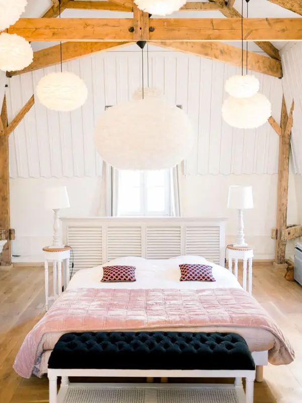 Guest room with pink bedspread and white beams, Château de Garde