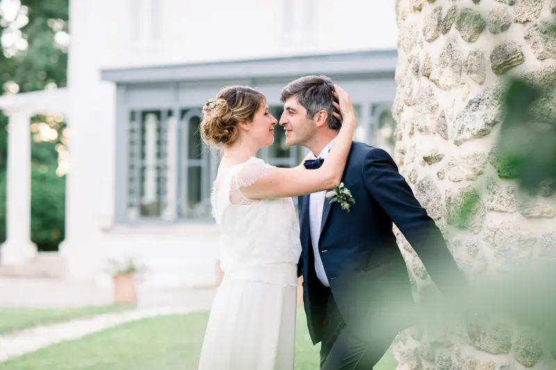 Bride and groom against the stone wall of Château de Seguin