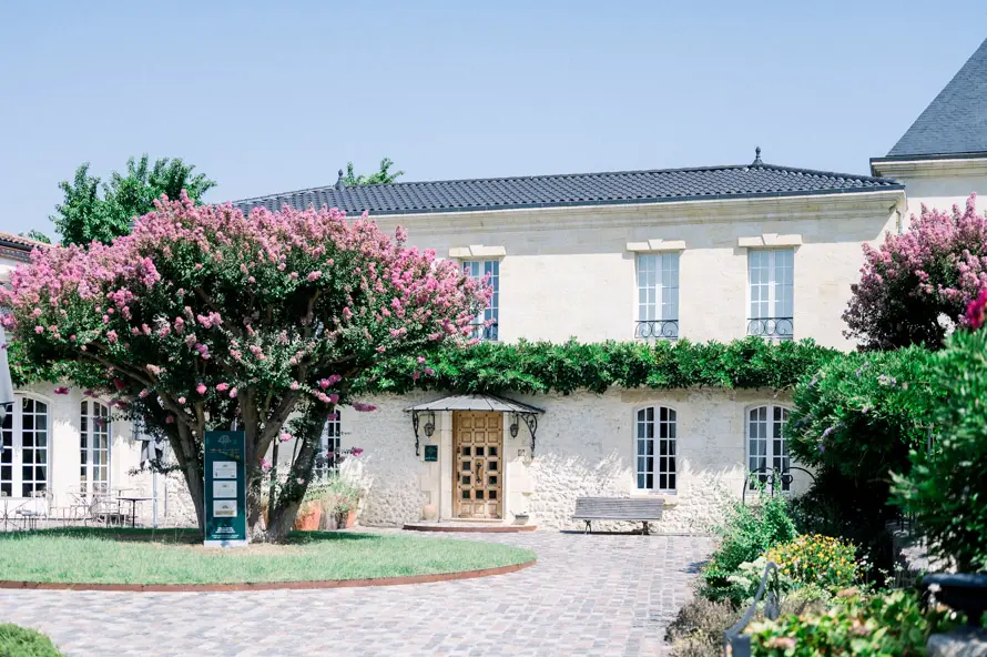 Façade of Domaine de Larchey with flowering trees, Saint-Médard-d'Eyrans