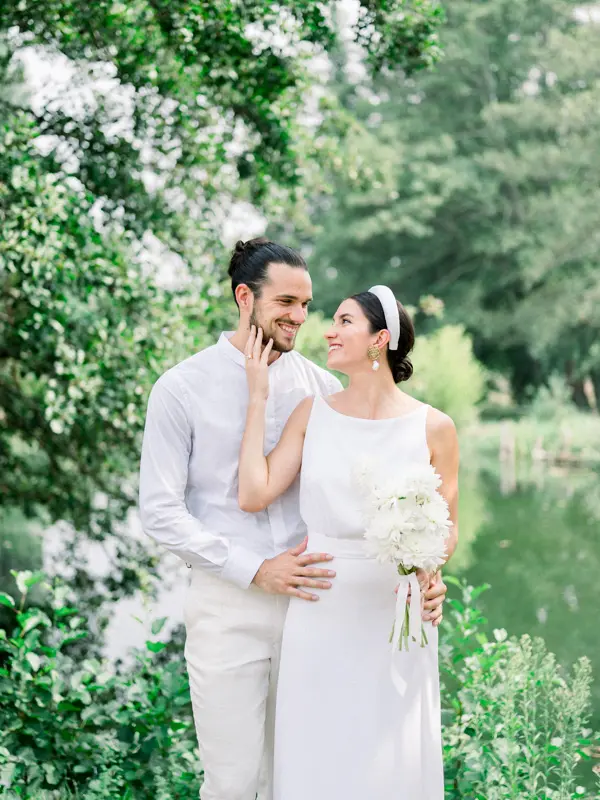 Bride and groom by the water in the gardens of Domaine de Larchey
