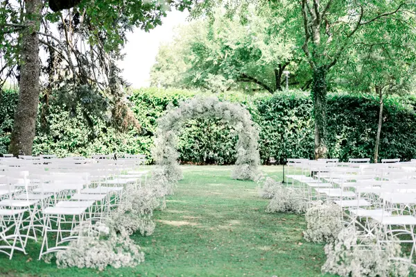 Outdoor ceremony with a gypsophila arch beneath the oaks, Domaine de Larchey