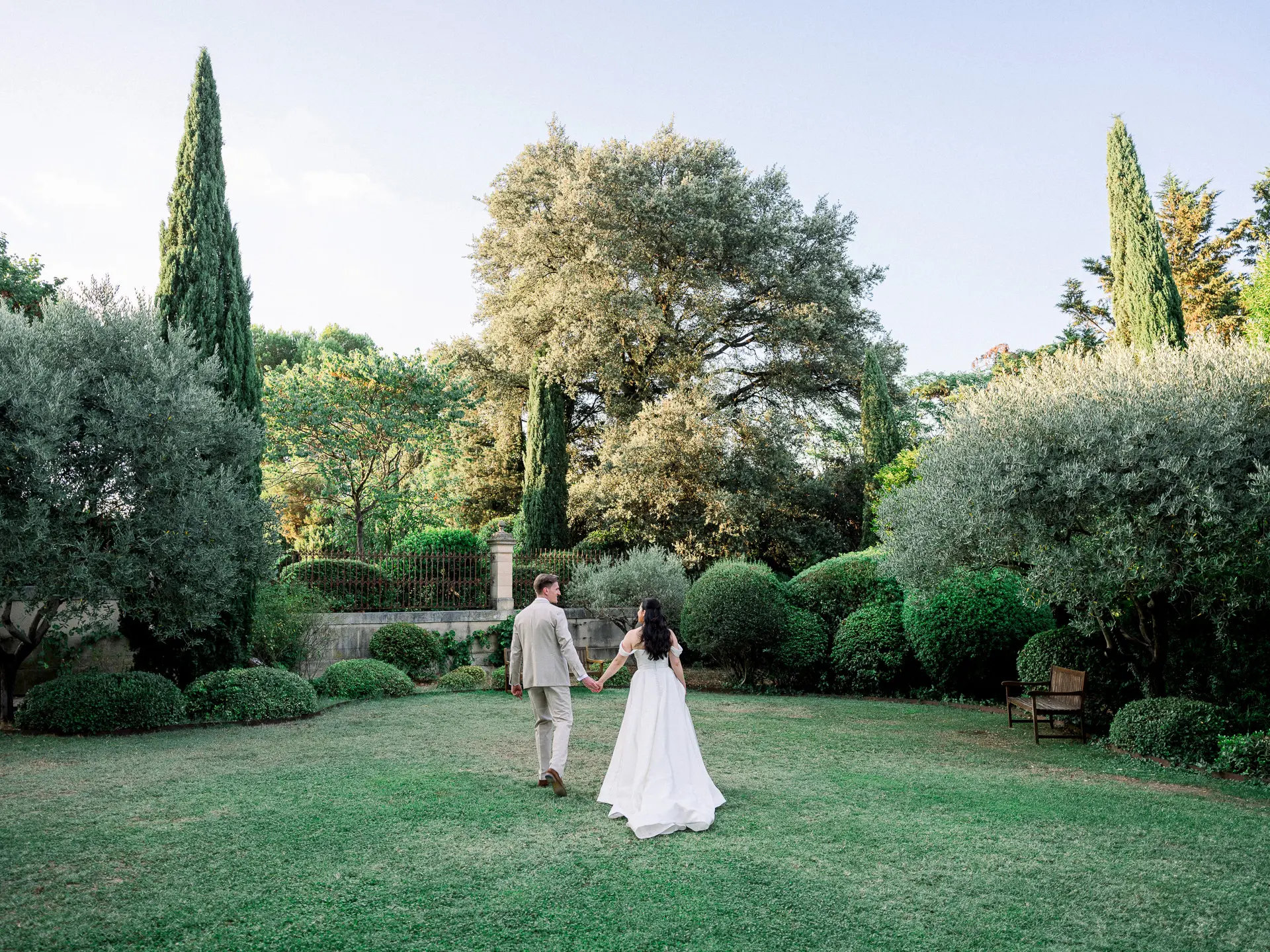 Mariés marchant main dans la main dans le jardin méditerranéen du Château La Tour Vaucros, en Provence