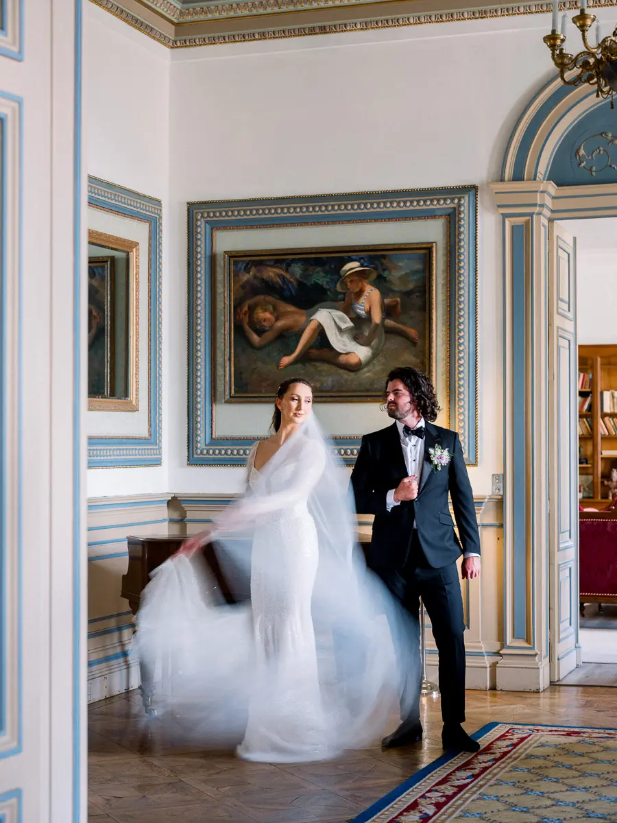 Mariée faisant virevolter son voile près du marié dans un salon du Château de la Valouze