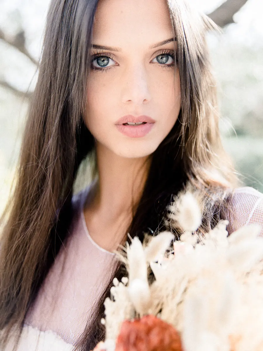 Portrait d'une jeune femme aux yeux clairs tenant des fleurs séchées