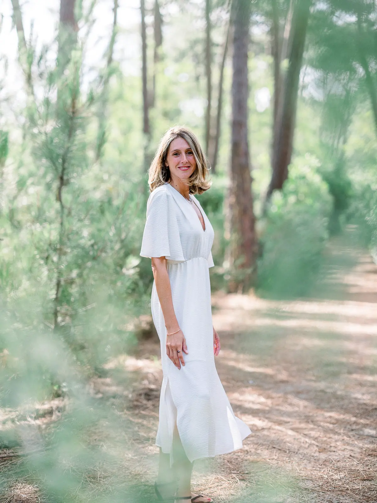 Woman in a white dress in a pine wood, natural light portrait