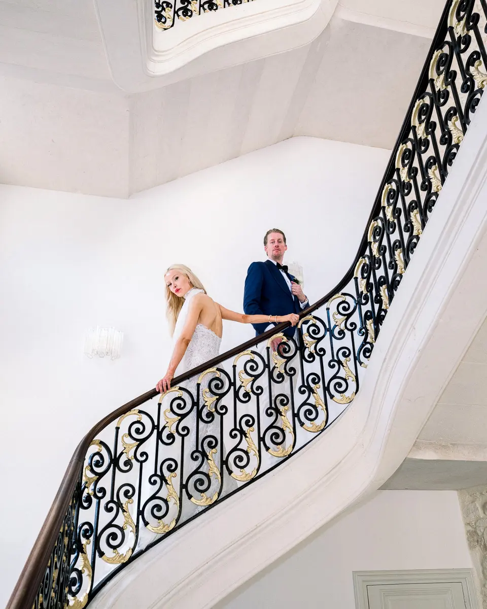 Bride and groom on a wrought-iron staircase in a château